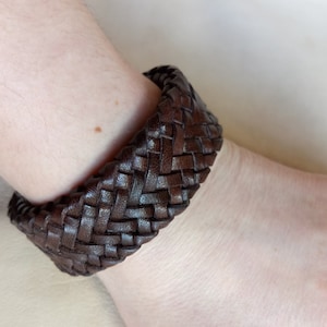 K&ouml;nnte beinhalten: Ein braunes Lederarmband mit geflochtenem Muster.