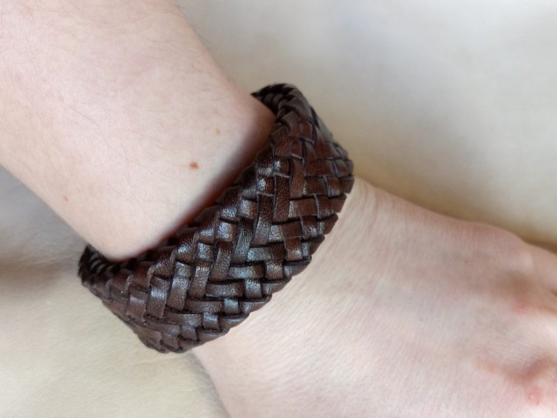 K&ouml;nnte beinhalten: Ein braunes Lederarmband mit geflochtenem Muster.