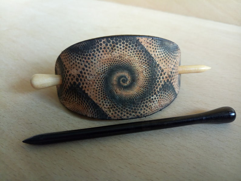 Op de afbeelding: Een bruine en zwarte haarstick met een spiraalpatroon. De stick is gemaakt van kurk en heeft een houten pin.