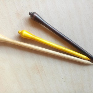 May include: Three wooden hair sticks, one natural wood color, one yellow, and one dark brown.