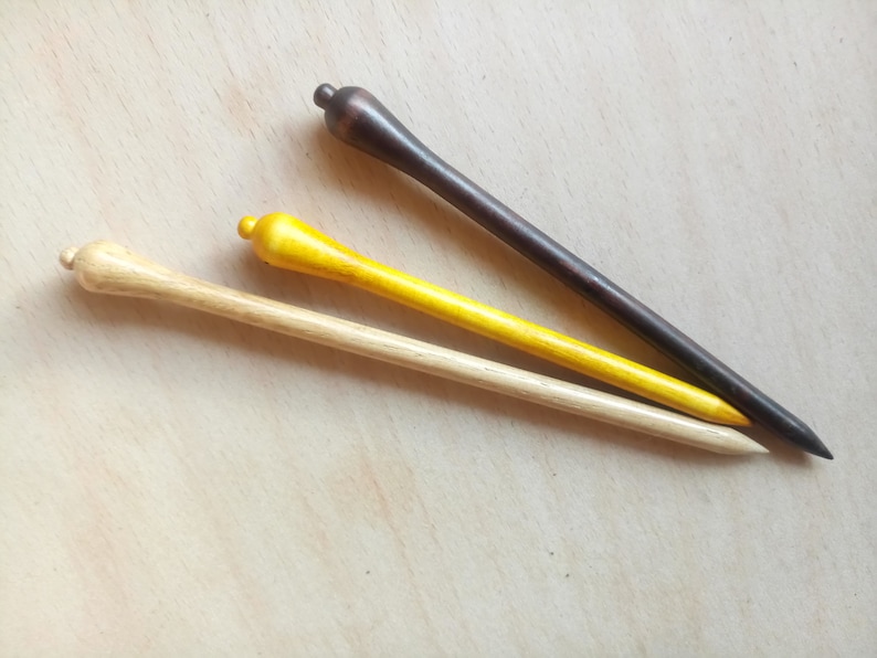 May include: Three wooden hair sticks, one natural wood color, one yellow, and one dark brown.