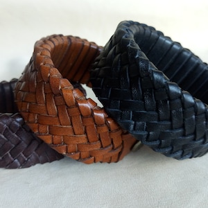 K&ouml;nnte beinhalten: Drei Lederarmb&auml;nder in Braun, Schwarz und Dunkelbraun, geflochten in einem Fischgr&auml;tenmuster.