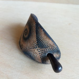 Op de afbeelding: Een zwarte en bruine haarstick met een spiraalpatroon. De stick is gemaakt van hout en heeft een gladde afwerking.