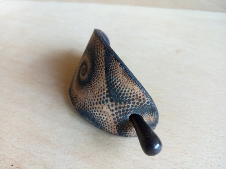Op de afbeelding: Een zwarte en bruine haarstick met een spiraalpatroon. De stick is gemaakt van hout en heeft een gladde afwerking.