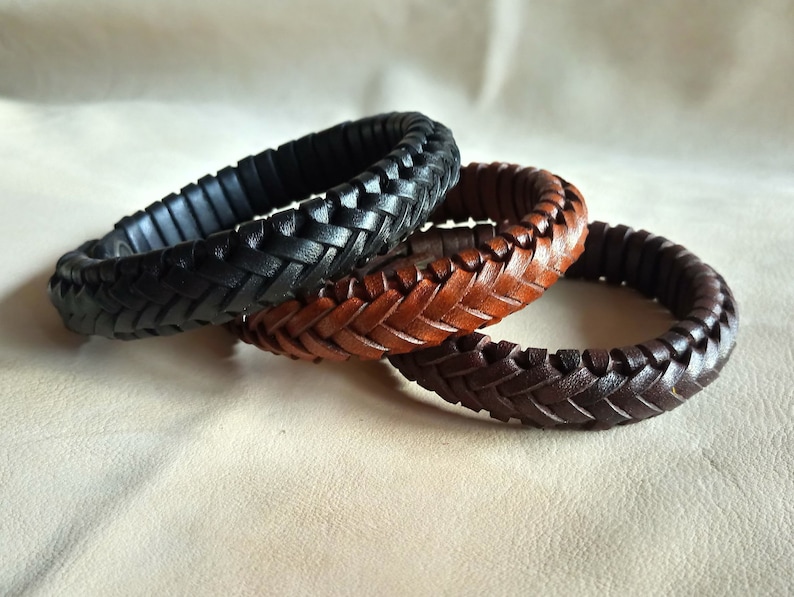 Puede incluir: Tres pulseras de cuero trenzado en negro, marr&oacute;n y beige. Las pulseras est&aacute;n apiladas una encima de la otra.