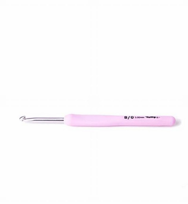 May include: A pink crochet hook with a silver metal hook and a rounded handle. The handle has the size 8/0 and 5.00mm printed on it. The crochet hook is designed for yarn crafts and knitting projects.