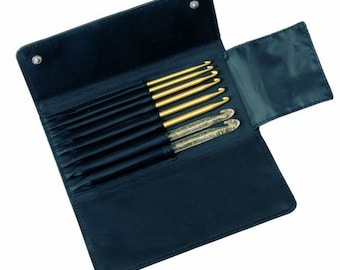 Könnte beinhalten: Ein schwarzes Lederetui mit einem Reißverschlussdeckel, das ein Set von acht goldenen Häkelnadeln enthält. Die Häkelnadeln sind nach Größe geordnet, wobei die größte Nadel oben und die kleinste Nadel unten liegt.