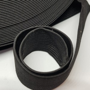 May include: Black elastic band, rolled up and folded, showing the texture of the fabric.