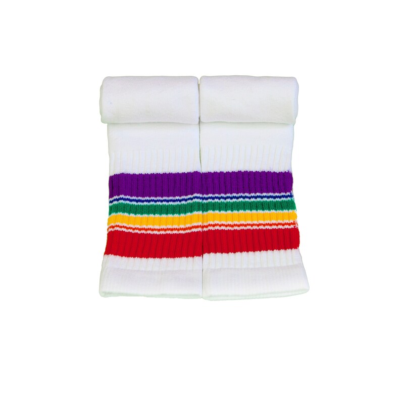 Op de afbeelding: Een paar witte sportsokken met een regenboogstreepontwerp. De sokken hebben een paarse, groene, gele en rode streep.