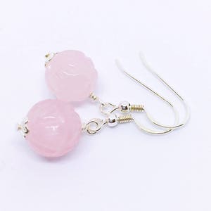 May include: A pair of silver earrings with pink carved rose quartz beads.