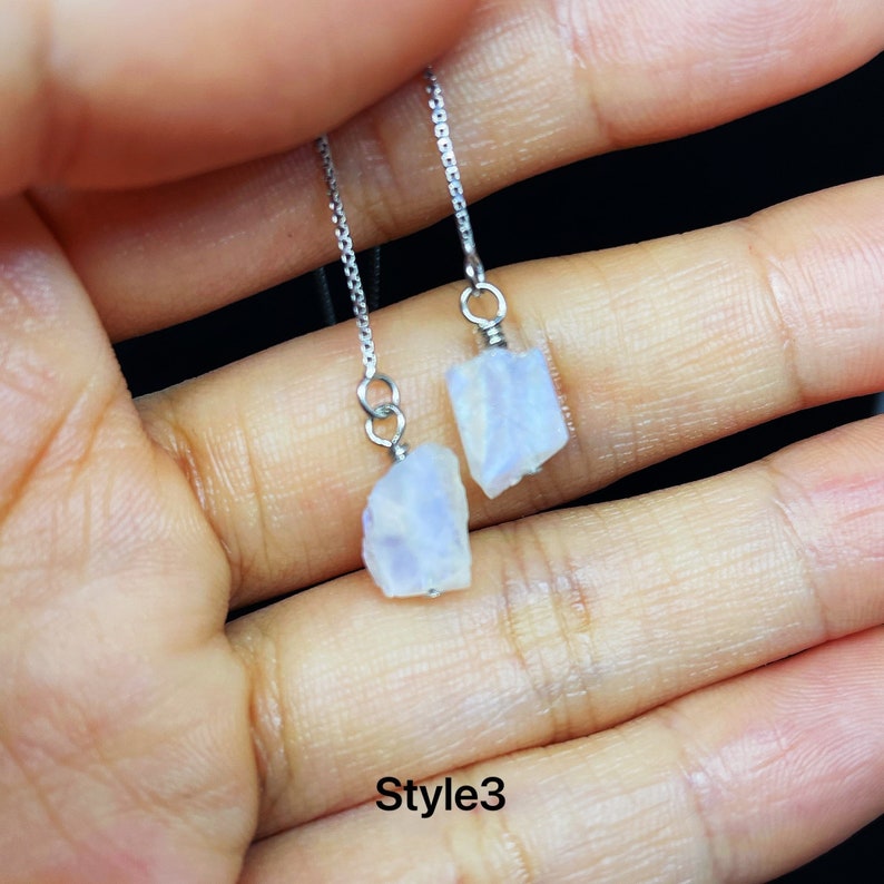 May include: A pair of silver chain earrings with iridescent moonstone teardrop-shaped charms. The earrings are labeled "Style3".
