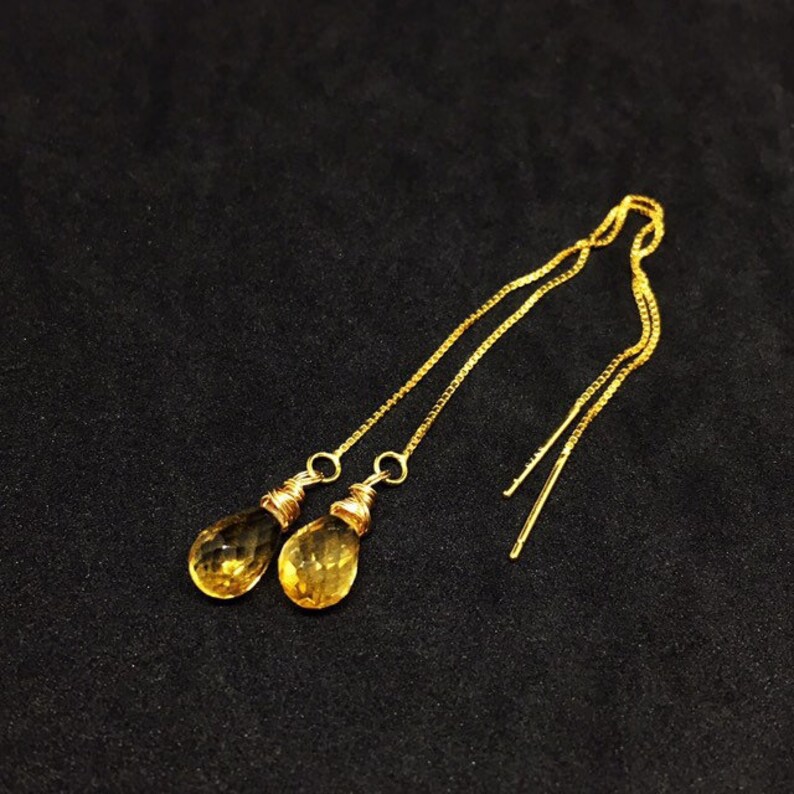 May include: A pair of gold dangle earrings with teardrop-shaped citrine stones.
