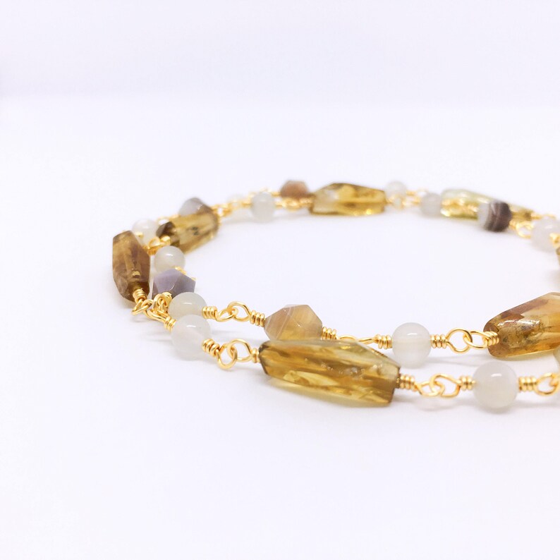 May include: A gold chain necklace with brown and white gemstone beads. The beads are faceted and have a natural, organic look.