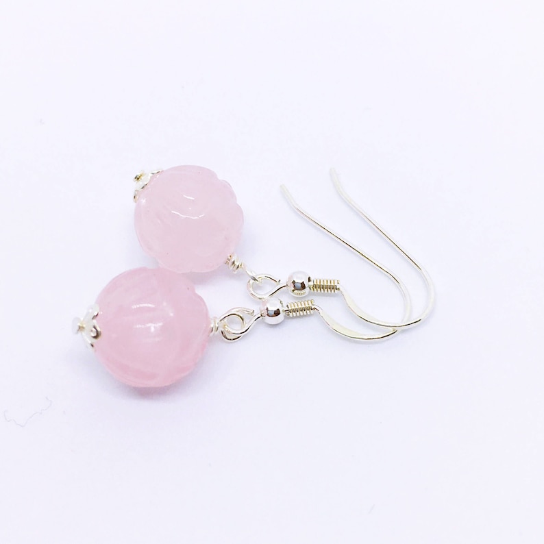 May include: A pair of silver earrings with pink carved rose quartz beads.