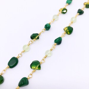 May include: A gold chain necklace with green and white gemstone beads. The necklace features a variety of green stones, including malachite and peridot.