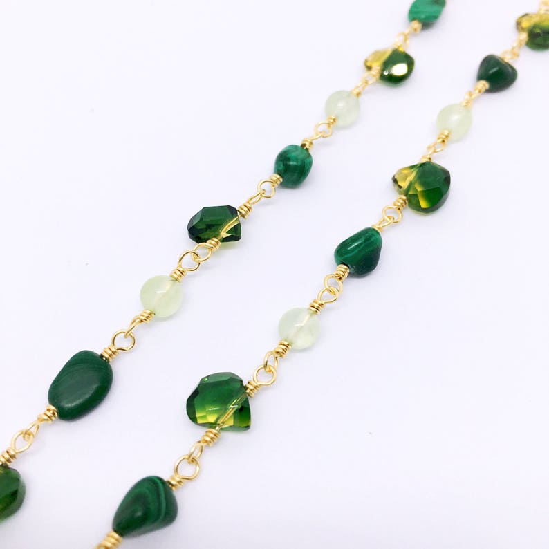 May include: A gold chain necklace with green and white gemstone beads. The necklace features a variety of green stones, including malachite and peridot.