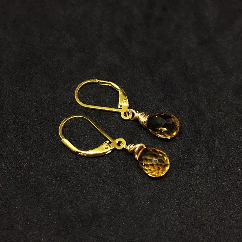 May include: A pair of gold earrings with teardrop-shaped topaz gemstones.
