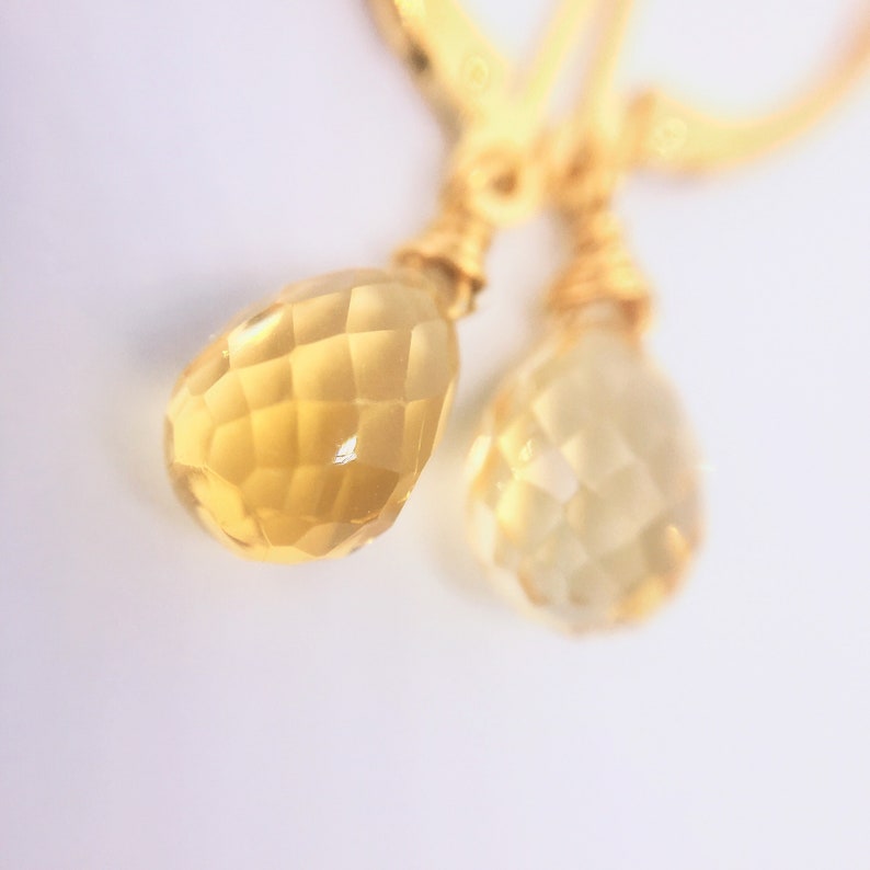 May include: A pair of gold earrings with teardrop-shaped citrine stones.