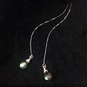May include: A pair of silver chain earrings with teardrop-shaped iridescent green labradorite stones.