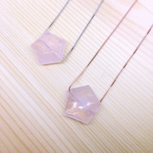 May include: Two rose quartz crystal necklaces with different chain styles. One necklace has a silver chain and the other has a rose gold chain.
