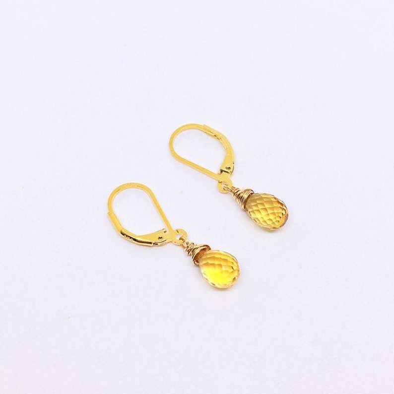 May include: A pair of gold earrings with teardrop-shaped yellow citrine stones.