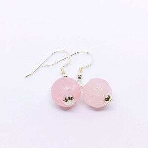 May include: A pair of silver earrings with pink, carved, round gemstone drops.