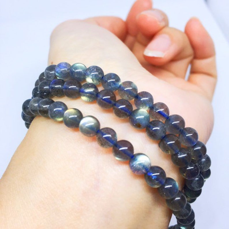 May include: A multi-strand necklace made of dark blue labradorite beads. The beads are round and have a slight iridescent sheen.