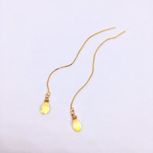 May include: A pair of gold dangle earrings with teardrop-shaped charms.