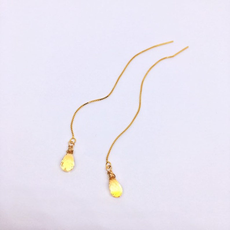 May include: A pair of gold dangle earrings with teardrop-shaped charms.
