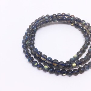 May include: A multi-strand bracelet made of dark blue labradorite beads. The beads are round and have a slight iridescent sheen.