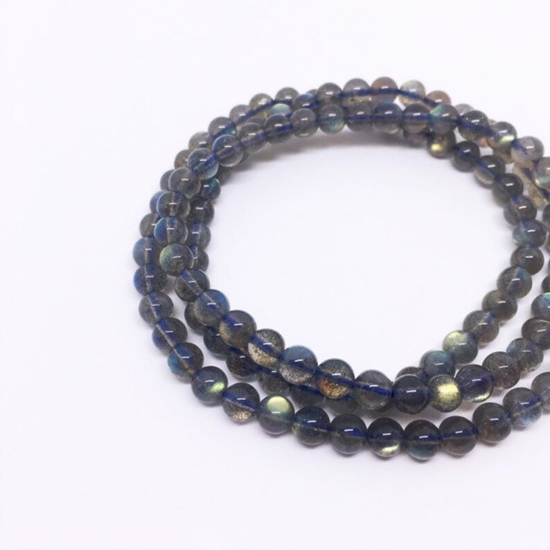 May include: A multi-strand bracelet made of dark blue labradorite beads. The beads are round and have a slight iridescent sheen.