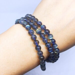 May include: A triple-strand bracelet made of dark blue labradorite beads. The beads are round and have a slight iridescent sheen.