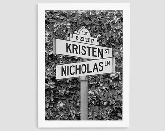 Könnte beinhalten: Schwarzweißfoto eines Straßenschilds mit den Namen "Kristen St" und "Nicholas Ln" und dem Datum "Est. 8.20.2017".