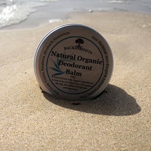 Op de afbeelding: Een ronde, zilveren blik met natuurlijke biologische deodorantbalsem met de merknaam "BACK2DROOTS" gedrukt op het etiket. Het etiket vermeldt ook "60g" en somt de ingredi&euml;nten op, waaronder "Antibacterieel Antifungaal & Dierproefvrij".