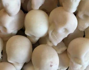 Puede incluir: Primer plano de numerosos objetos pequeños con forma de calavera, de color blanquecino. Las calaveras están agrupadas, con detalles visibles como cuencas de los ojos y mandíbulas. Los objetos parecen estar hechos de un material liso, posiblemente comestible.