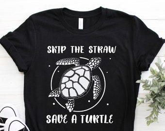 May include: Black t-shirt with a white graphic of a sea turtle inside a circle, and the text "SKIP THE STRAW SAVE A TURTLE". Black and white sneakers are in the foreground. A small green plant is to the right.