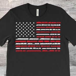May include: Black t-shirt with a white silhouette of an American flag made up of train engines and cars. The red stripes of the flag are filled in with red.