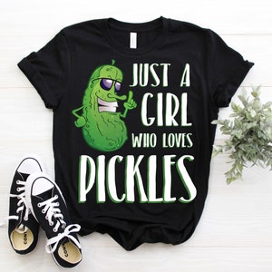 Może przedstawiać: Czarny t-shirt z zielonym kresk&oacute;wkowym og&oacute;rkiem w okularach przeciwsłonecznych i tekstem "Just a girl who loves pickles".