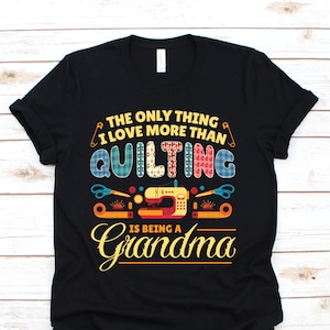 May include: Black t-shirt with a colorful graphic design. The text reads "THE ONLY THING I LOVE MORE THAN QUILTING IS BEING A Grandma." The design includes images of sewing tools and a sewing machine.
