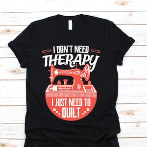 Puede incluir: Camiseta negra con el texto "I DON'T NEED THERAPY I JUST NEED TO QUILT." El diseño presenta una ilustración de máquina de coser roja. La camiseta está hecha de un material suave y tiene un cuello redondo clásico.