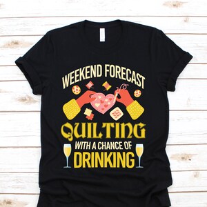 May include: Black t-shirt with the text "WEEKEND FORECAST QUILTING WITH A CHANCE OF DRINKING." The design includes illustrations of quilting tools, a heart-shaped quilt, and champagne glasses.