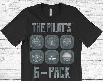 May include: Black t-shirt with a grey graphic showing six aviation instrument gauges and the text "THE PILOT'S 6-PACK" in grey lettering. The shirt is made of a soft material.