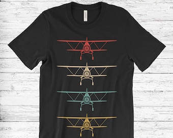 May include: Black t-shirt with a retro design of four vintage airplanes in different colors. The airplanes are facing forward and have a propeller in the front.