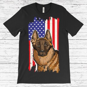 May include: Black t-shirt with a brown dog illustration set against a distressed American flag design. The flag features blue stars and red and white stripes. The dog appears to be a German Shepherd or a similar breed, with a vintage aesthetic.