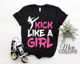 May include: Black t-shirt with a white silhouette of a person kicking and the text "Kick Like A Girl" in pink.