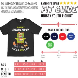 May include: Black youth t-shirt with a graphic of a cat sitting in a chair reading a book. The text on the shirt reads "Easily Distracted By Books and Cats". The shirt is available in sizes S, M, L, and XL. The size chart shows the age range, width, and length of each size in inches.