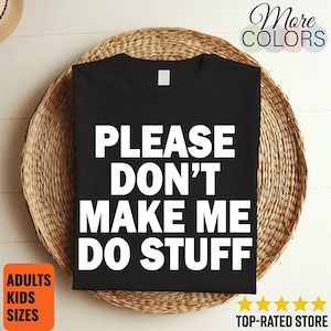 May include: Black t-shirt with the white text "PLEASE DON'T MAKE ME DO STUFF." The shirt is displayed on a woven, circular placemat. The image also includes text that says "ADULTS KIDS SIZES" and "TOP-RATED STORE."