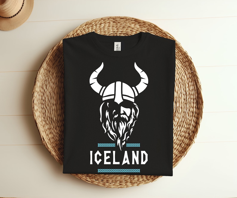 May include: Black t-shirt with a white graphic of a Viking wearing a horned helmet and a beard. The text "ICELAND" is printed below the graphic.