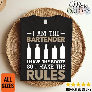 Pode incluir: Camiseta preta com texto branco e bege que diz "I AM THE BARTENDER I HAVE THE BOOZE SO I MAKE THE RULES." A camisa apresenta ilustrações de garrafas brancas. As palavras "More Colors", "All Sizes" e "Top-Rated Store" também são visíveis.