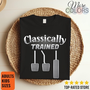 Könnte beinhalten: Schwarzes T-Shirt mit dem silberfarbenen Schriftzug "Classically Trained" und einer Grafik von Autopedalen. Der Aufdruck enthält auch die Texte "More Colors", "Adults Kids Sizes" und "Top-Rated Store".